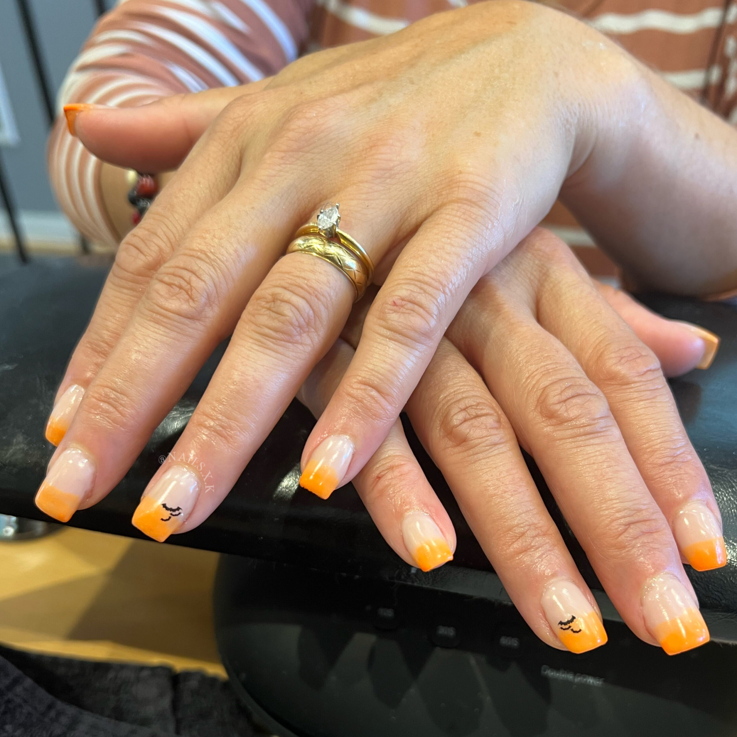 Short acrylic set with orange ombre and bat accent nails. Nails by K