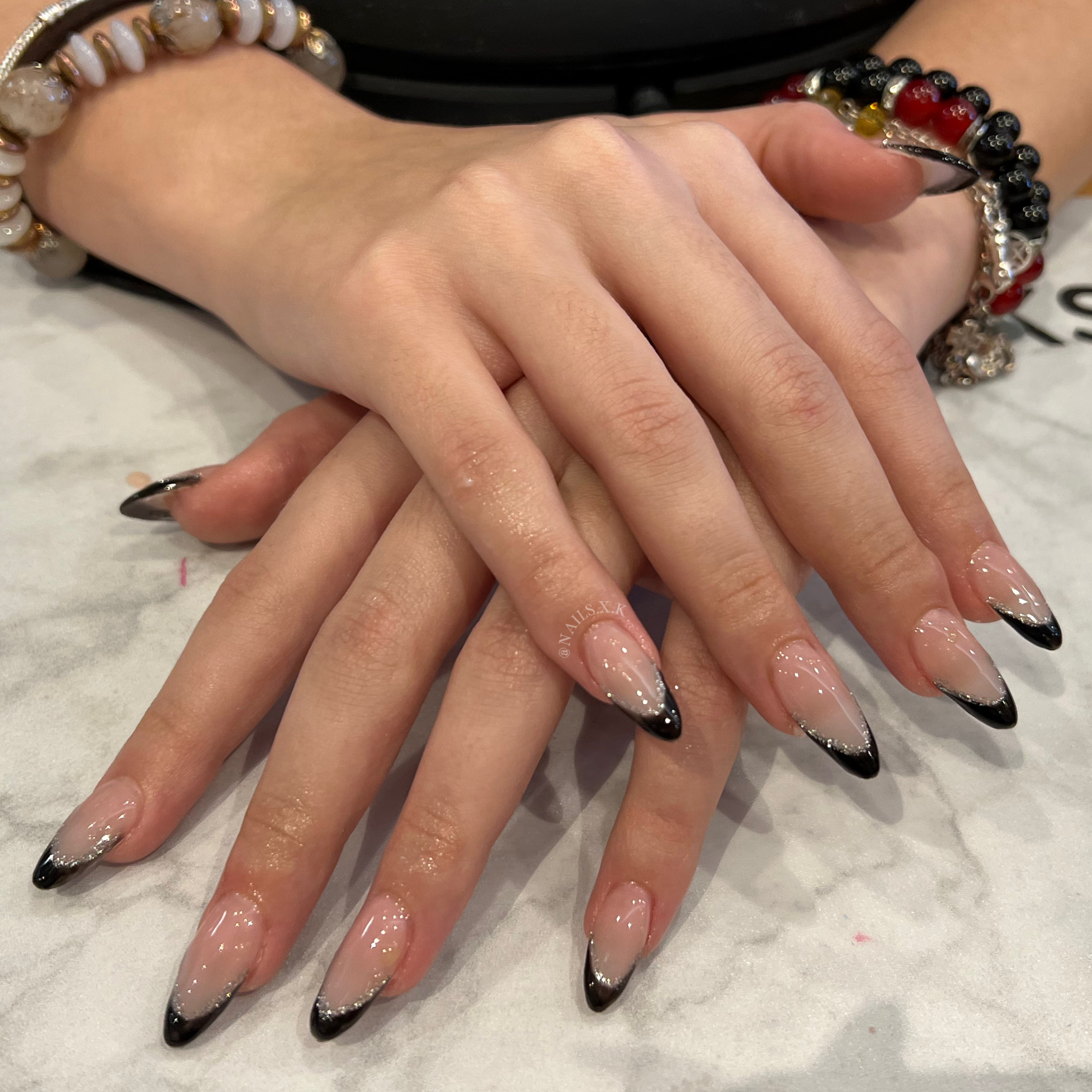 Acrylic full set of nails with black hand painted french tips and silver glitter. Nails by K