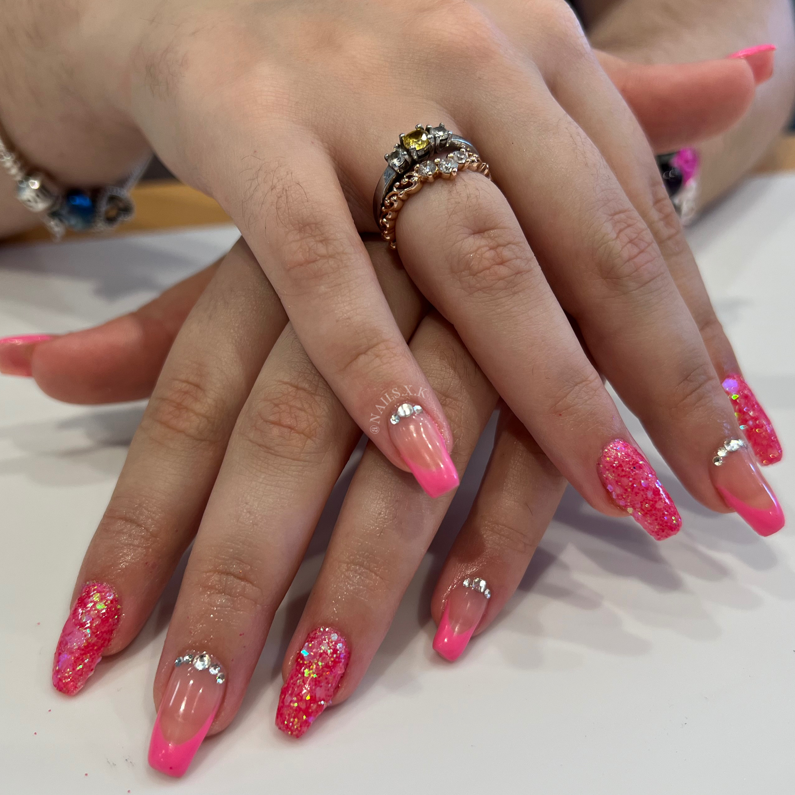 Hard gel with pink french and glitter press designs and accented with crystal rhinestones. Nails by K